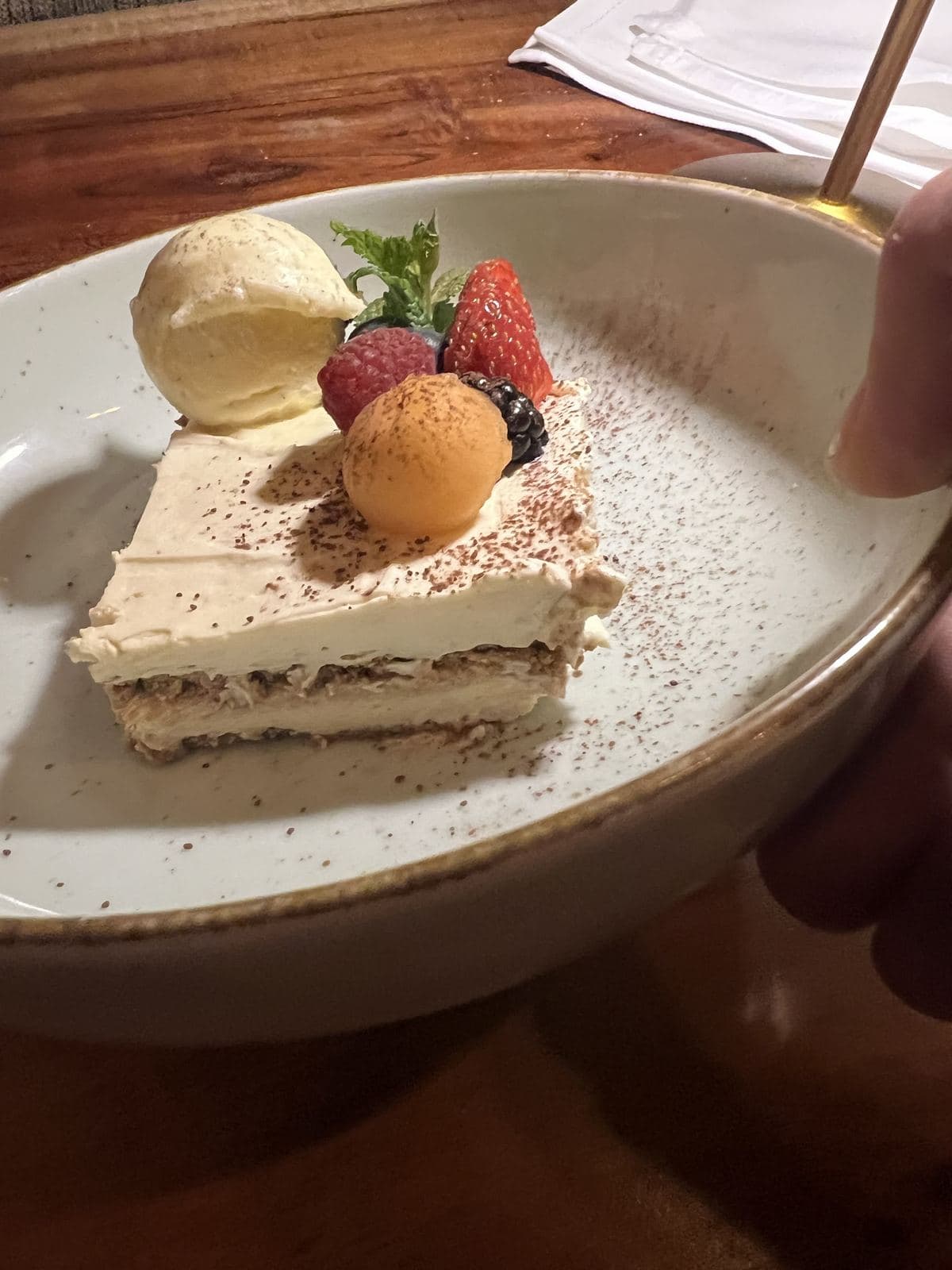 Une part de gâteau en couches crémeuses, une boule de glace, une boule de sorbet et des fruits rouges