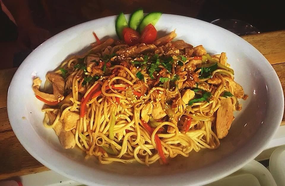 Des nouilles sautées aux légumes et à la viande, dans une grande assiette ovale