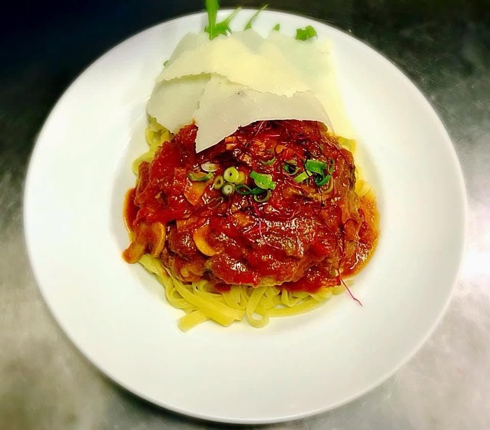 Des tagliatelles sous une sauce tomate à la viande, avec des copeaux de parmesan