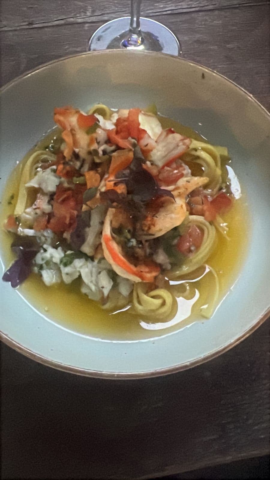 Un bol de pâtes dans un bouillon clair, garni de fruits de mer et de légumes