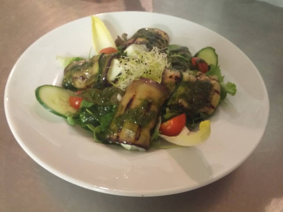 Des aubergines grillées roulées sur un lit de salade, avec tomates cerise et concombre