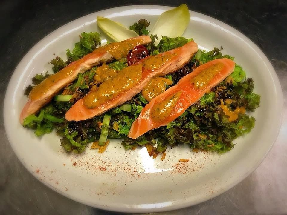 Trois pavés de saumon posés sur un lit de salade, nappés d'une sauce dorée