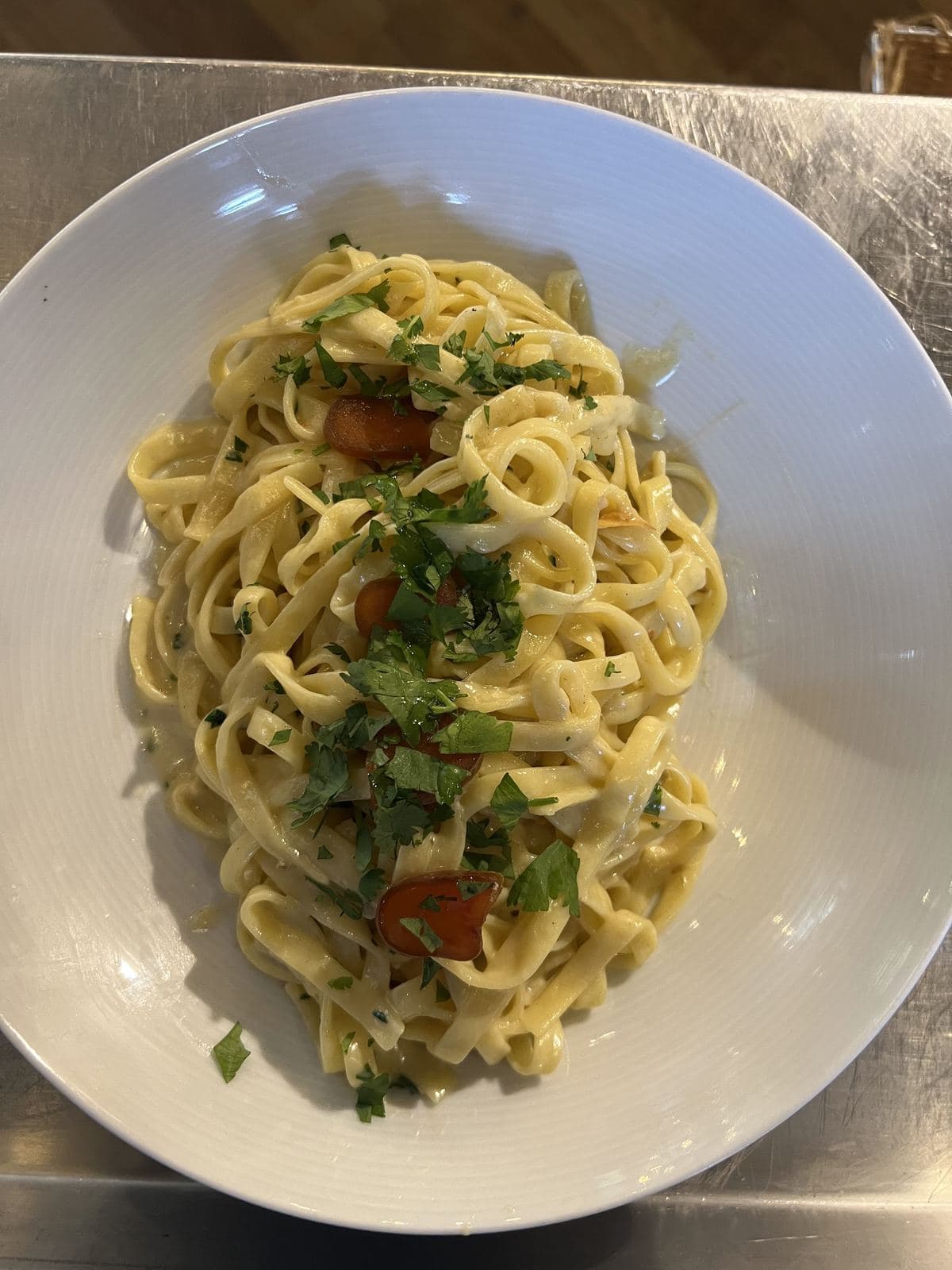 Tagliatelle met kruiden en kerstomaten, in een wit diep bord